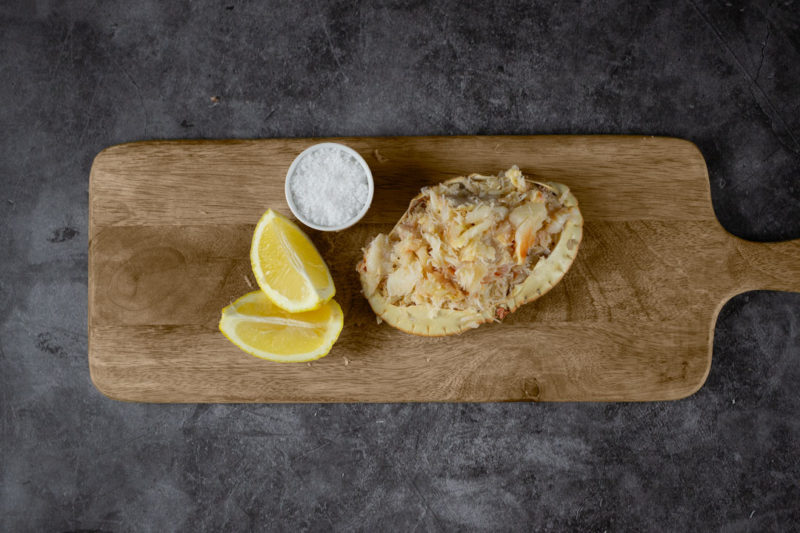 Dressed Crab on a wooden board with lemon and salt