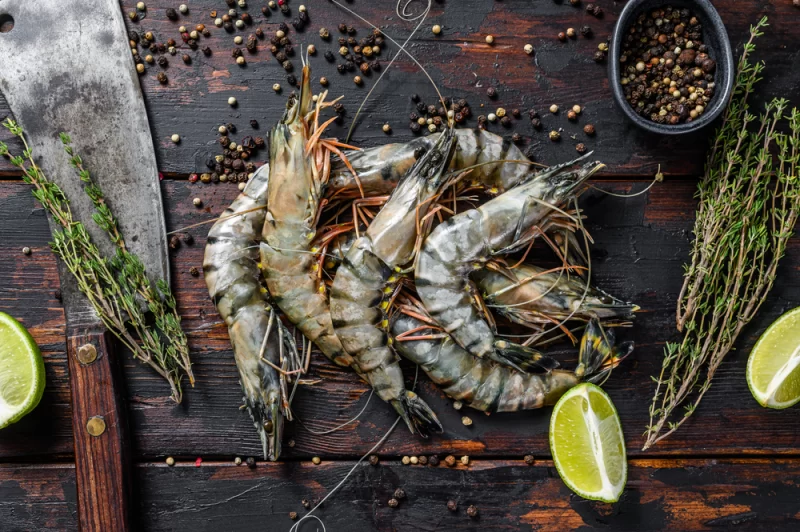Raw whole black tiger king prawns with pepper and lemon